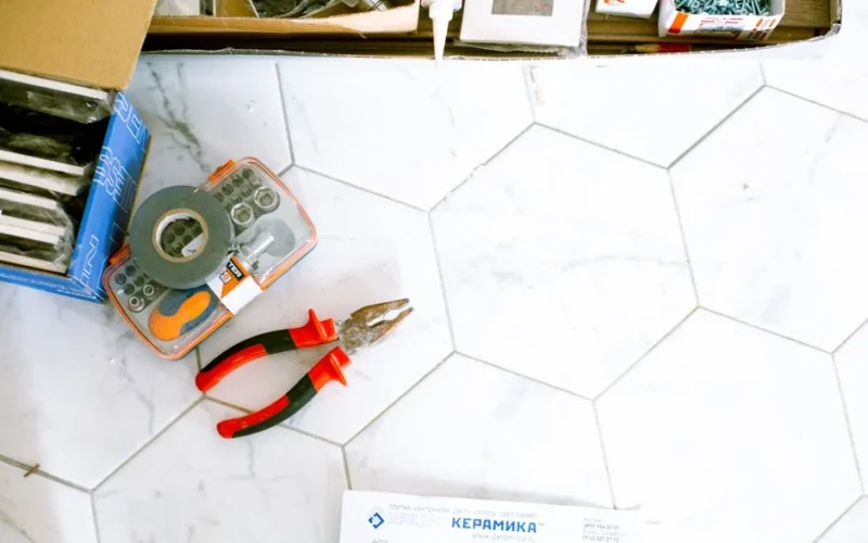 A selection of home renovation tools placed on a white tiled floor, ready for use.