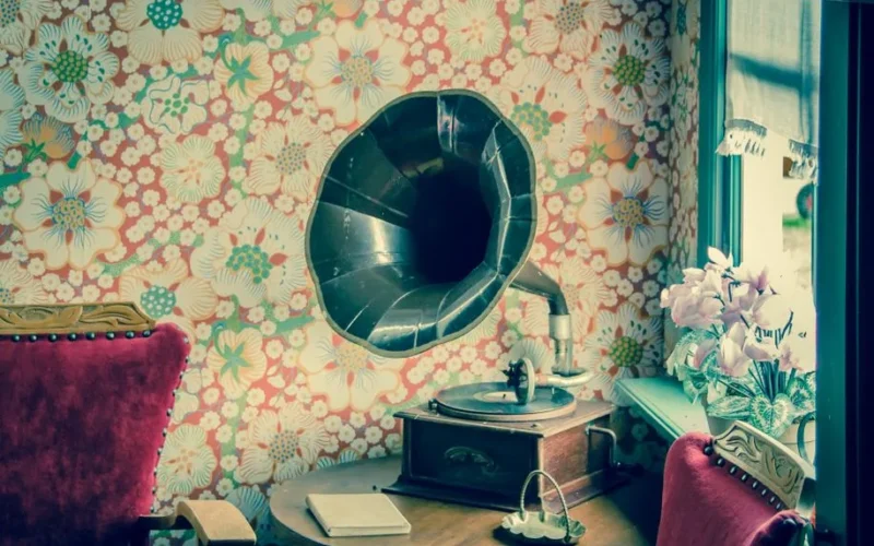 Retro gramophone in a room with floral wallpaper and vintage decor.