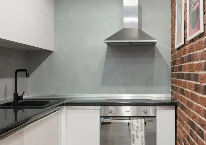 Contemporary kitchen interior with stainless steel appliances and brick wall.