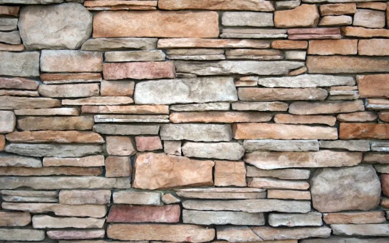 High-resolution image of a natural stone wall with various textures and earthy tones.