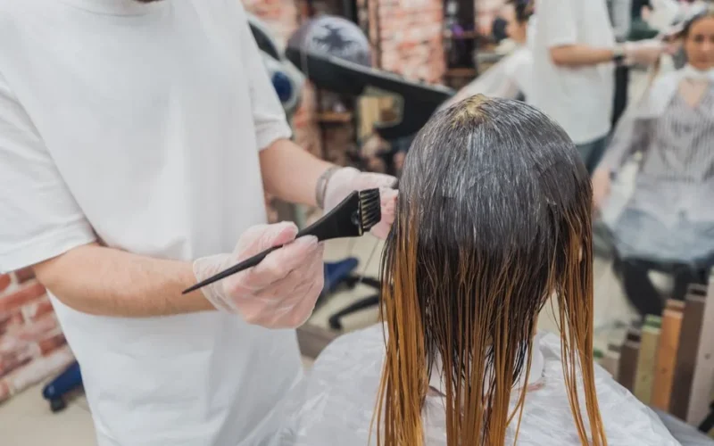 Hair coloring process in a salon, showcasing stylist applying color to client's hair.
