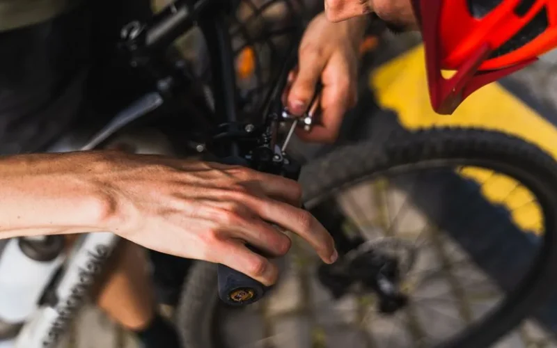Detailed shot of a person adjusting a bicycle handlebar outdoors in daylight.